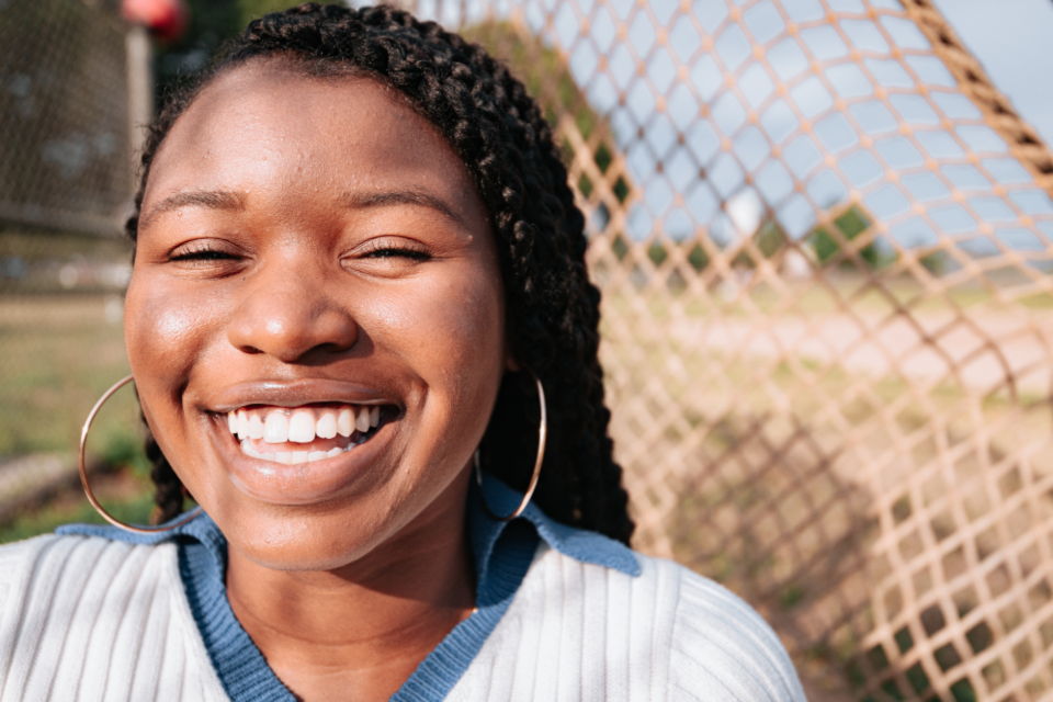 Confident young woman with a warm, genuine smile in natural outdoor light