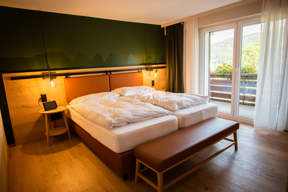 A warm, inviting bedroom with crisp white bedding, soft natural light and a peaceful mountain view through the window, evoking restful sleep