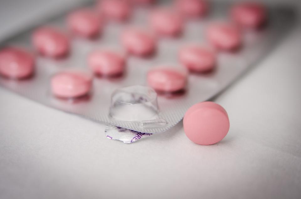 A blister pack of pink tablets with a single tablet placed beside it on a clean white surface, representing a discreet course of prescription treatment